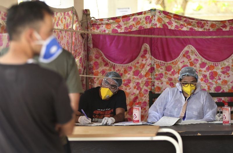 An Indian doctor interacts with a man as another waits for his turn at COVID-19 screening facility inside a government run hospital in Jammu.  (Photo by Channi Anand/AP Photo)
